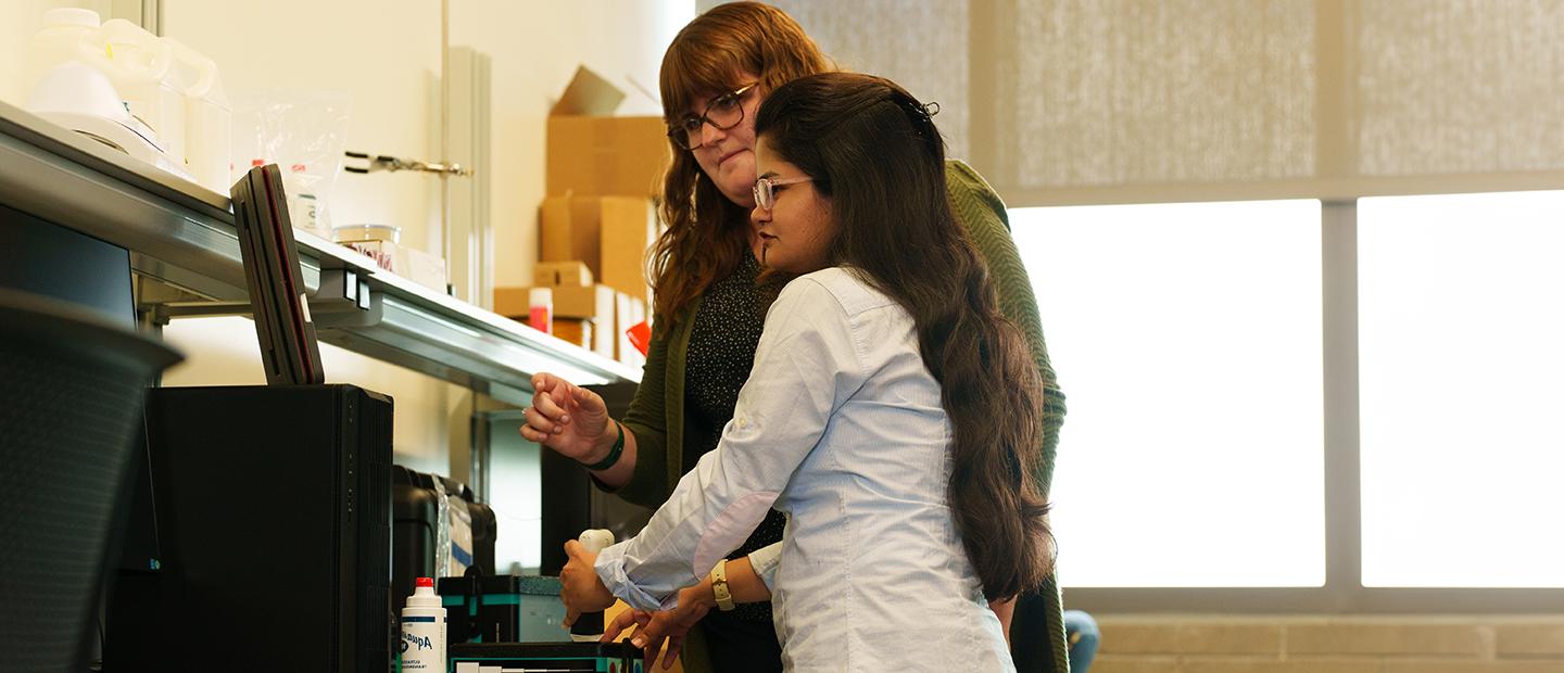 A professor and a student looking at a computer screen